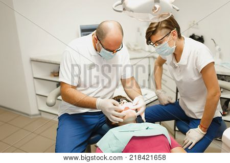 Process Of Preparing And Installing Dental Ceramic Crown. Male Professional Dentist And Female Assis