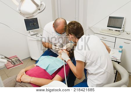 Process Of Preparing And Installing Dental Ceramic Crown. Male Professional Dentist And Female Assis