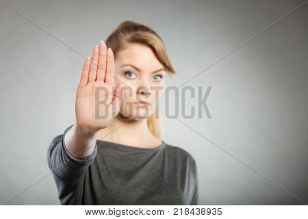 Prohibition symbol. Serious female shows stop sign talk to hand gesture. Angry full of negative emotions woman with hand palm stopping.