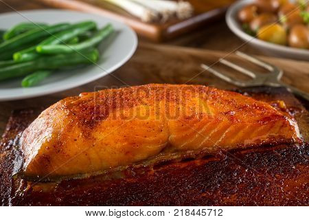 A delicious portion of barbecued cedar planked salmon with green beans and potatoes.