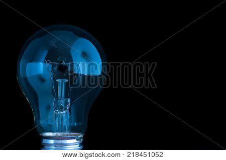 Blue light bulb isolated on black background.