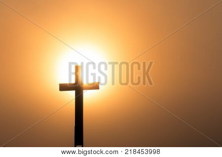 Catholic cross in sundown, in dense fog.