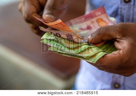Closeup photograph of hands counting srilankan rupies