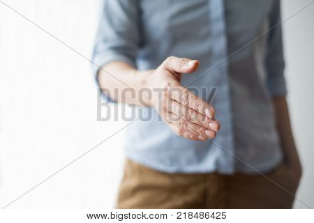 Cropped view of person extending arm for handshake. Front view.