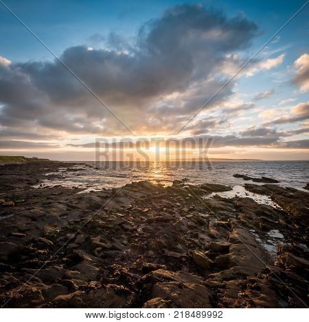 Scottish sunset and coastline. A wide angle HDR view from John O'Groats in the north of Scotland with the isle of Stroma visible in the distance set against a dramatic dusky sunset.