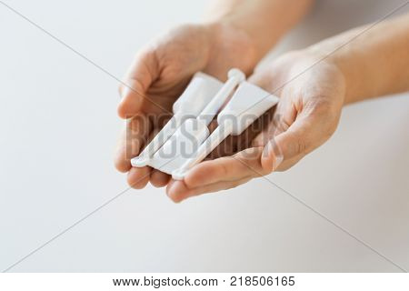 medicine, healthcare and pharmaceutics concept - hands holding tubes of micro enema