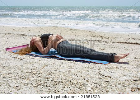 Ung kvinde gør Yoga øvelse på stranden i fisk udgør