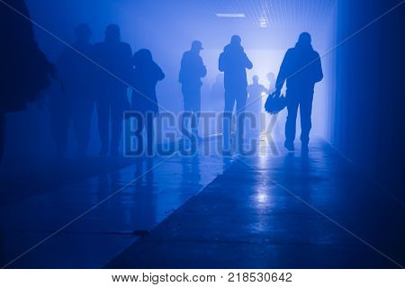 silhouette of people walking in a tunnel in smoke against a background of bright light. mysterious mood