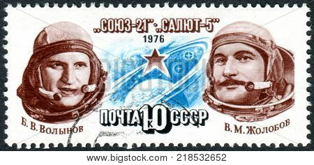 USSR - CIRCA 1976: A stamp printed in USSR dedicated to exploits of Soyuz-21 and Salyut-5 space station shows cosmonauts V. V. Volynov V. M. Zholobov Star Circling Globe circa 1976