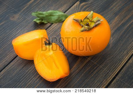 A sweet bright persimmon close-up on dark rustic wooden table