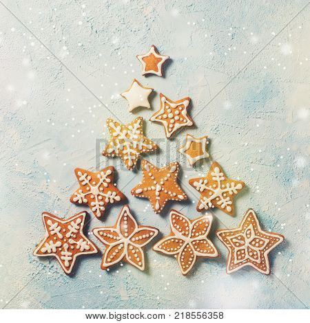 Christmas fir of gingerbreds stars over blue texture. Square