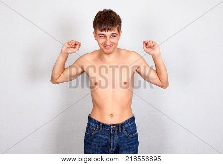 Weak Young Man Muscle Flexing on the White Wall Background