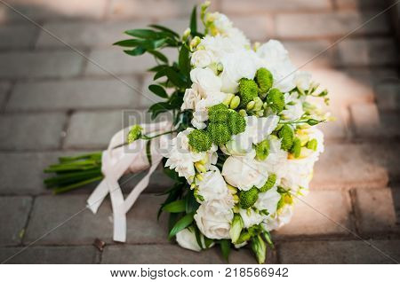 White And Green Wedding Bouquet Lying On The Pavement