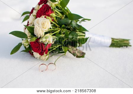 Wedding Rings And Bouquet Lying On The Snow