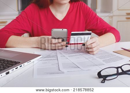 Attractive Female Student With Ginger Hair Bun Thinks About Coursework Strategy, Works With Laptop C