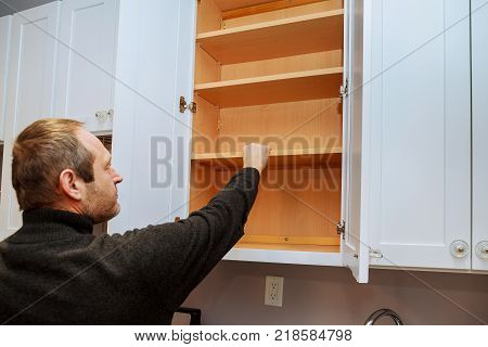 Closeup of a cabinet installer installing hardware on new kitchen cabinets. Installing new kitchen