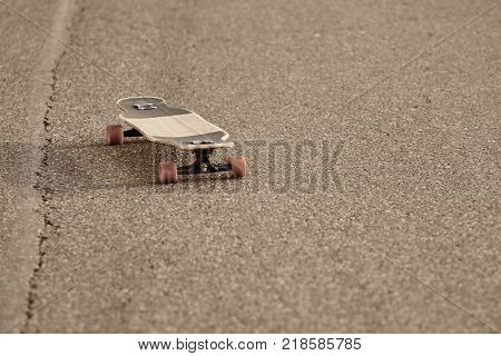 Hobby leisure extreme activity and sports. Isolated outdoor shot of stylish longboard resting on blank empty road with copy space for your information or advertising content. Selective focus