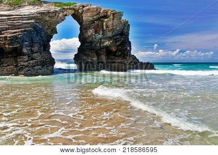 The rock in the form of an arch on the ocean beach. Northern Spain Praia de Augas Santas sunny summer day