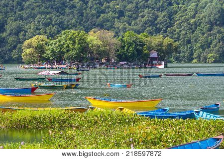 POKHARA NEPAL - September 29 2013: Tourists on old small boats sailing on the Phewa lake. Rowboat symbol of Phewa lakeside in Pokhara city.