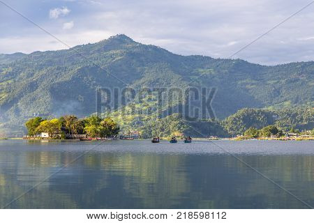 POKHARA NEPAL - September 29 2013: Tourists on old small boats sailing on the Phewa lake. Rowboat symbol of Phewa lakeside in Pokhara city.