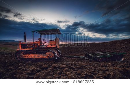Old rusty tractor in a field on sunset.HDR image.