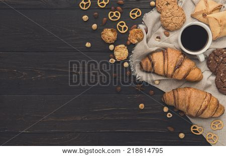 French croissants and coffee background. Tasty french breakfast with variety of homemade cookies, nuts and buns. Mockup for sweet pasrty recipe, top view, copy space