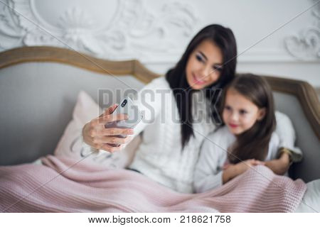 Well-groomed hand of a woman holding a phone taking a selfie with her daughter, little girl.