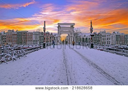 Snowy Amsterdam with the Thiny bridge in the Netherlands at sunset