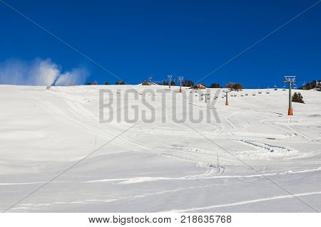 Chairlift without people. The cable car on the blue sky in the Dolomites. Cableway in the mountains without people. Artificial snowing ski slope by Snow cannon maker. Alpe di Siusi, Italy in winter.