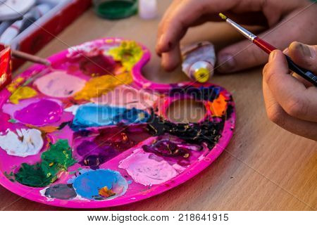 Palette of watercolor paints. Hand with paintbrush. Art concept