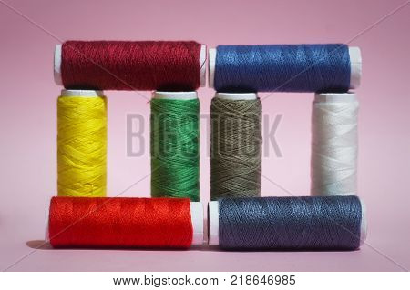 Multicolored threads on a pink background, red, blue, yellow, green