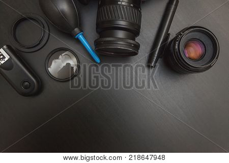 top view of work space photographer with dslr camera system, camera cleaning kit and camera accessory on black table background with copy space