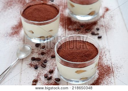 Three portions of traditional Italian dessert tiramisu on wooden table.