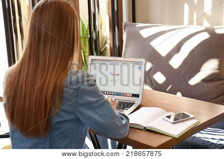 KIEV, UKRAINE - SEPTEMBER 28, 2017: Young woman using Apple Macbook Air with Google search page on screen in cafe