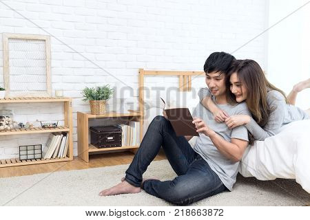 Asian couple or lover reading book in the bedroom. Relaxing lifestyle on weekend. Have copyspace on left. Lifestyle couple in love concept.