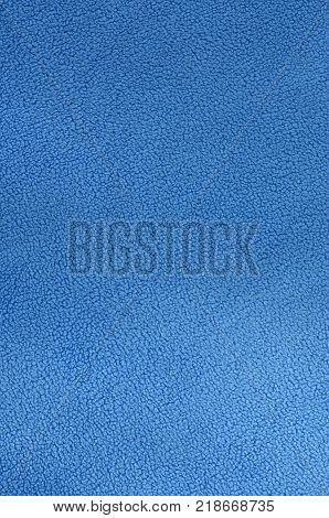 The blanket of furry blue fleece fabric. A background texture of light blue soft plush fleece material