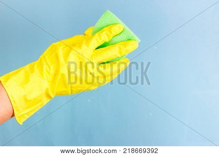 Washing windows and glass. The worker in a yellow glove can stack a sponge with foam on a blue background