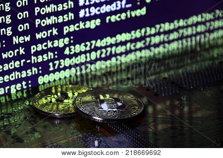 The digital process of cryptocurrency mining by using the GPUs. Bitcoins and video card on a working display and mining screen
