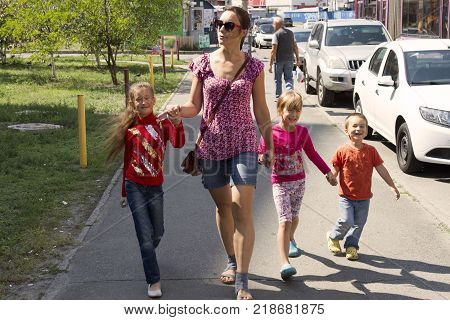Happy mother with three happy children walking along the street