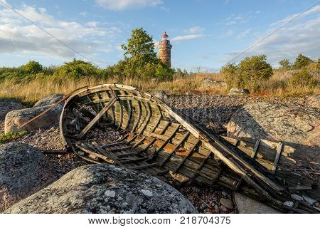 Lighthouse and old boat in the Baltic Sea. Shore, evening light, sunset, clouds and architecture concept. Mohni, small island in Estonia, Europe.