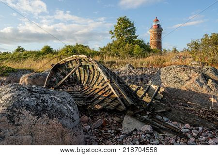 Lighthouse and old boat in the Baltic Sea. Shore, evening light, sunset, clouds and architecture concept. Mohni, small island in Estonia, Europe.