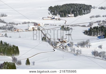 Idyllic rural countryside on snowy winter day. Aerial view of barnyards and farms. Weitnau, Allgau, Bavaria, Germany. Typical bavarian cultured landscape.