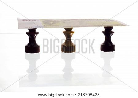 three chess pawns black and white holding a banknote on white background. Money or business or worship or slavery or bank concept