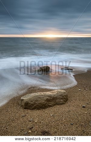 Beautiful Vibrant Sunset Landscape Image Of Burton Bradstock Golden Cliffs In Dorest England