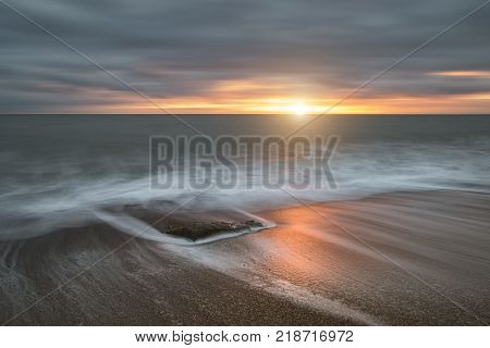 Beautiful Vibrant Sunset Landscape Image Of Burton Bradstock Golden Cliffs In Dorest England