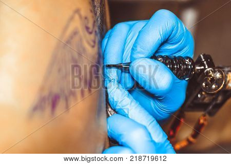 Russia, Novokuzneck, 5.07.2017: tattooer showing process of making a tattoo hands holding a tatoo machine