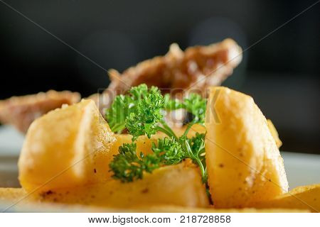 Little restaurant bowl served with goldy fried potato slices, thin roasted sausage and decorated with fresh parsley leaves. Looks very delicious and nourisihing.
