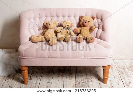Three teddy bears sitting on pink sofa