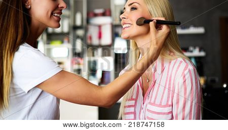 Makeup artist applying liquid tonal foundation on the face of the woman. Beauty and fashion concept