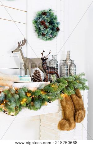 Mantelpiece with Christmas decorations. Cozy winter scene. White interior details with lights